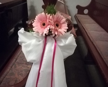 Dekoracja ławki w kościele tkaninami i żywymi kwiatami