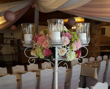 Świecznik z żywymi kwiatami na stole gości weselnych
